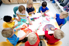 overhead shot of a group of children sitting around a preschool table doing colorful finger-painting